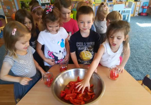 Grupa dzieci wkłada paprykę do słoików.